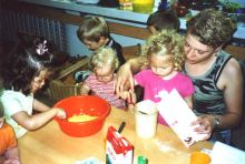 Kinder und Erzieherin beim Backen